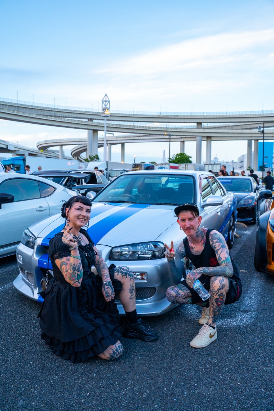 Tour guests with a Nissan Skyline R34 GT-R at Daikoku PA under the expressway