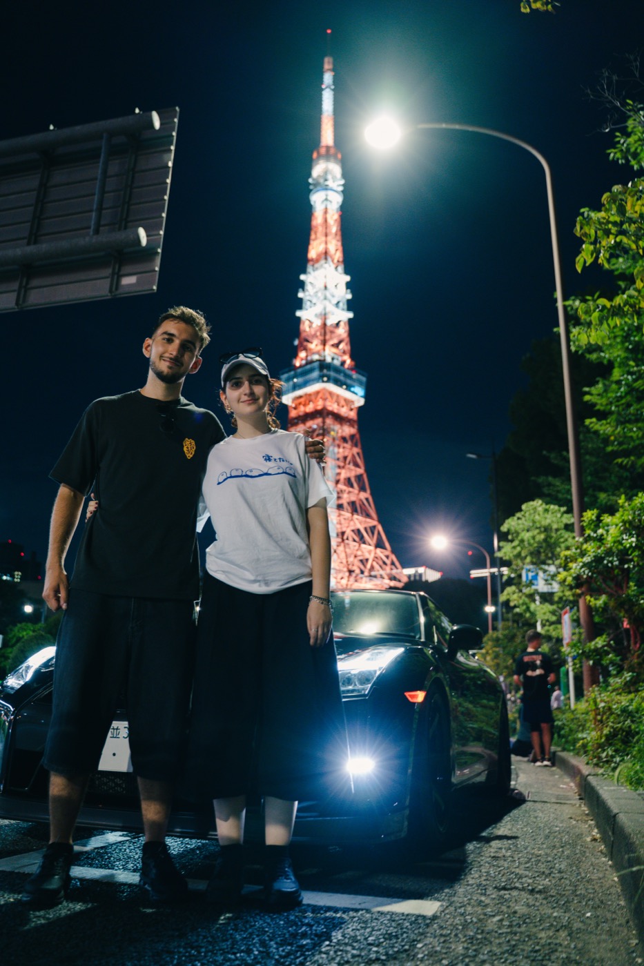 Creators posing with a Nissan GT-R under Tokyo Tower at night
